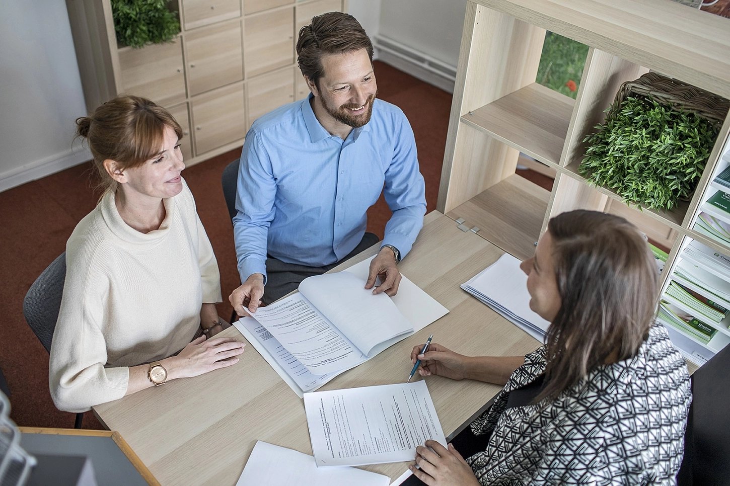 Bankadviseur van Alitos bespreekt contractdetails met een klant aan een bureau.